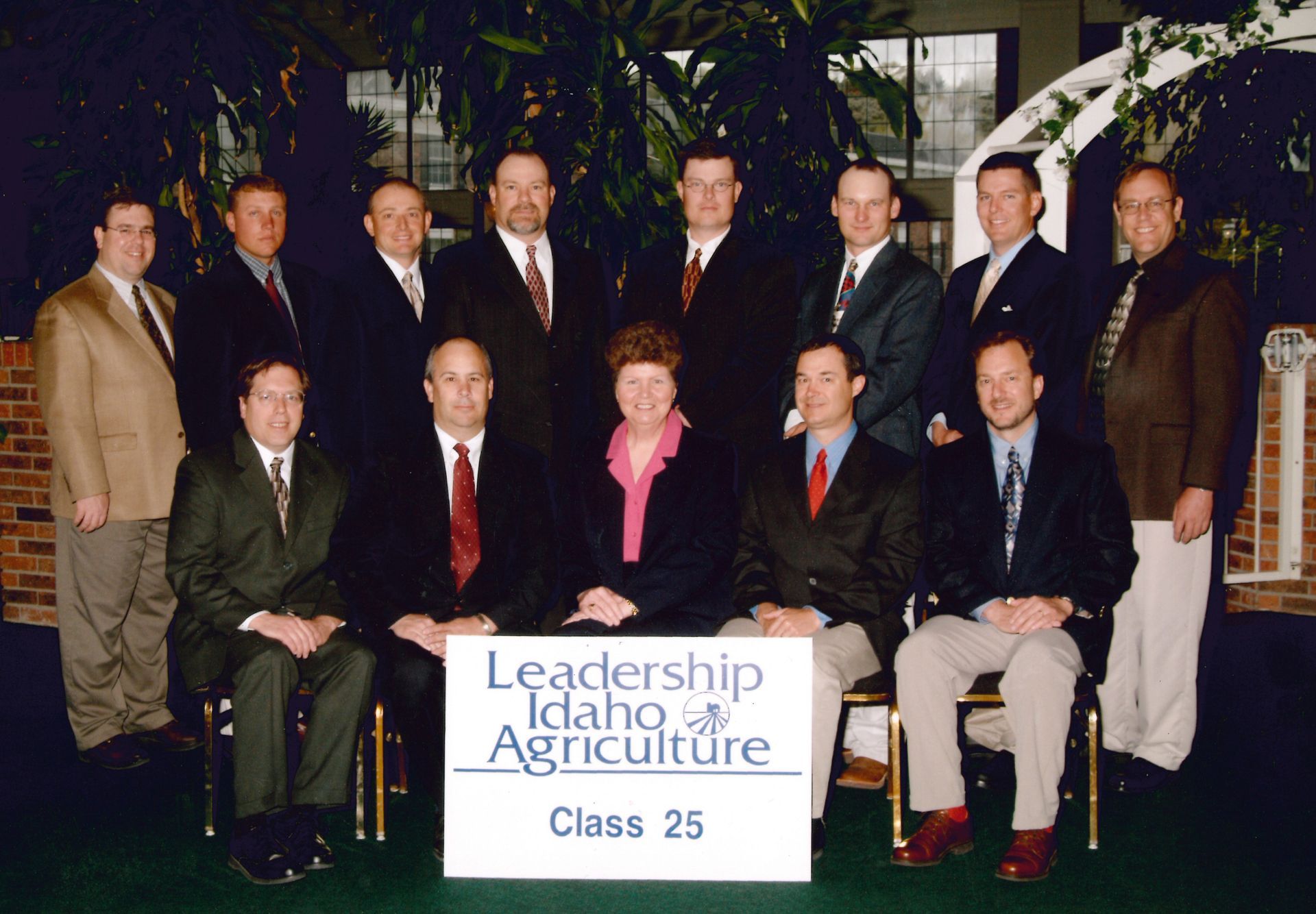 A group of people standing and sitting behind a sign that reads, 
