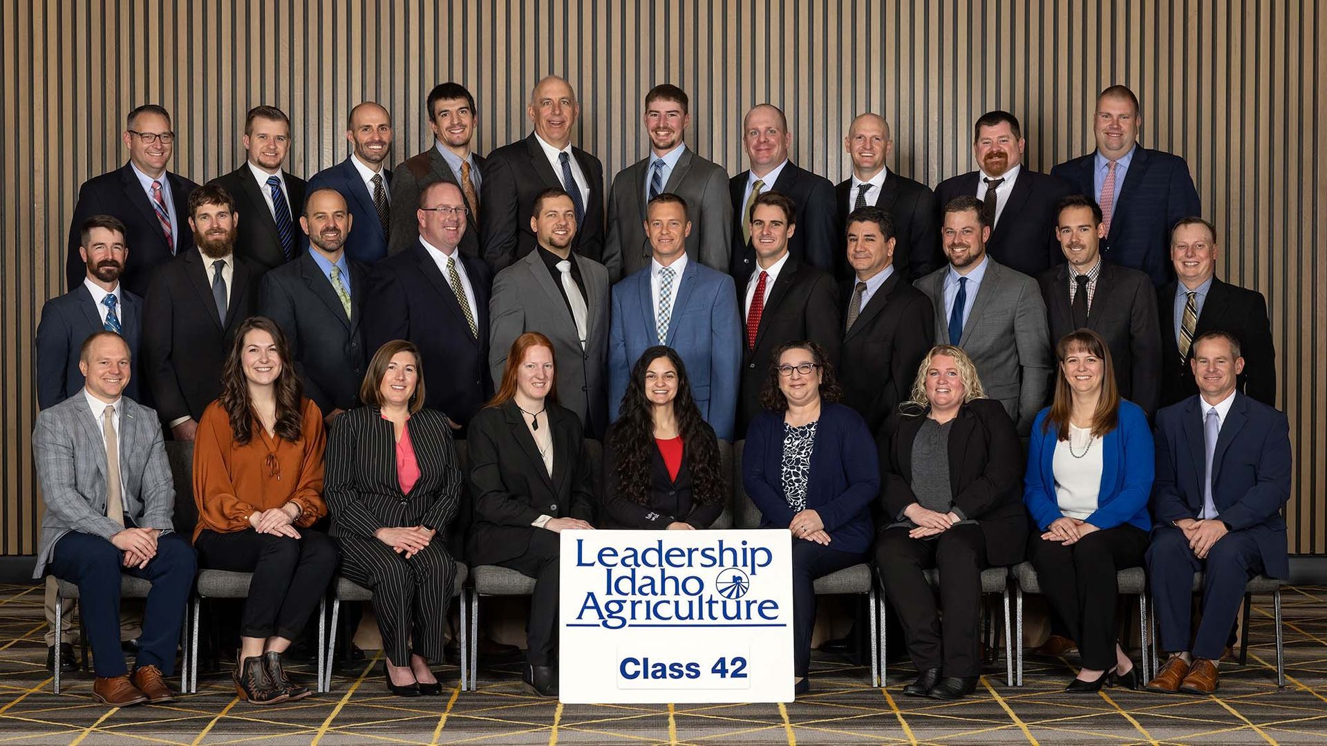 Group portrait of the Leadership Idaho Agriculture Class 42 in business attire in front of a neutral backdrop.