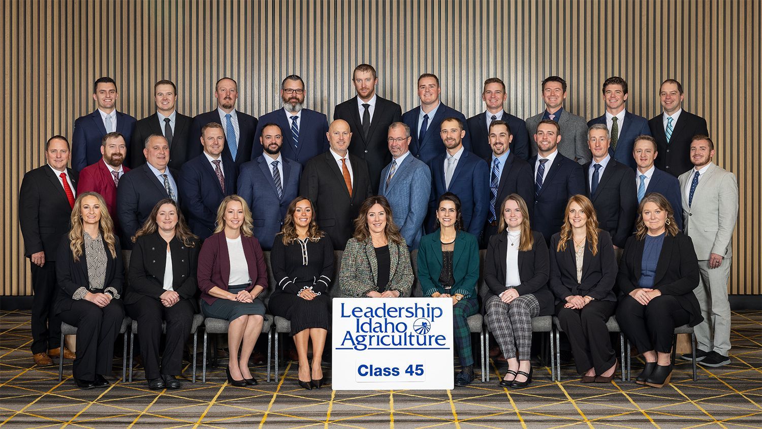 A group portrait of the Leadership Idaho Agriculture Class 45, posed formally in front of a striped wall.