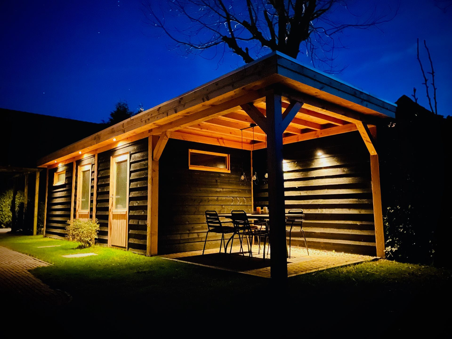 Een houten huis met een overdekt terras 's nachts