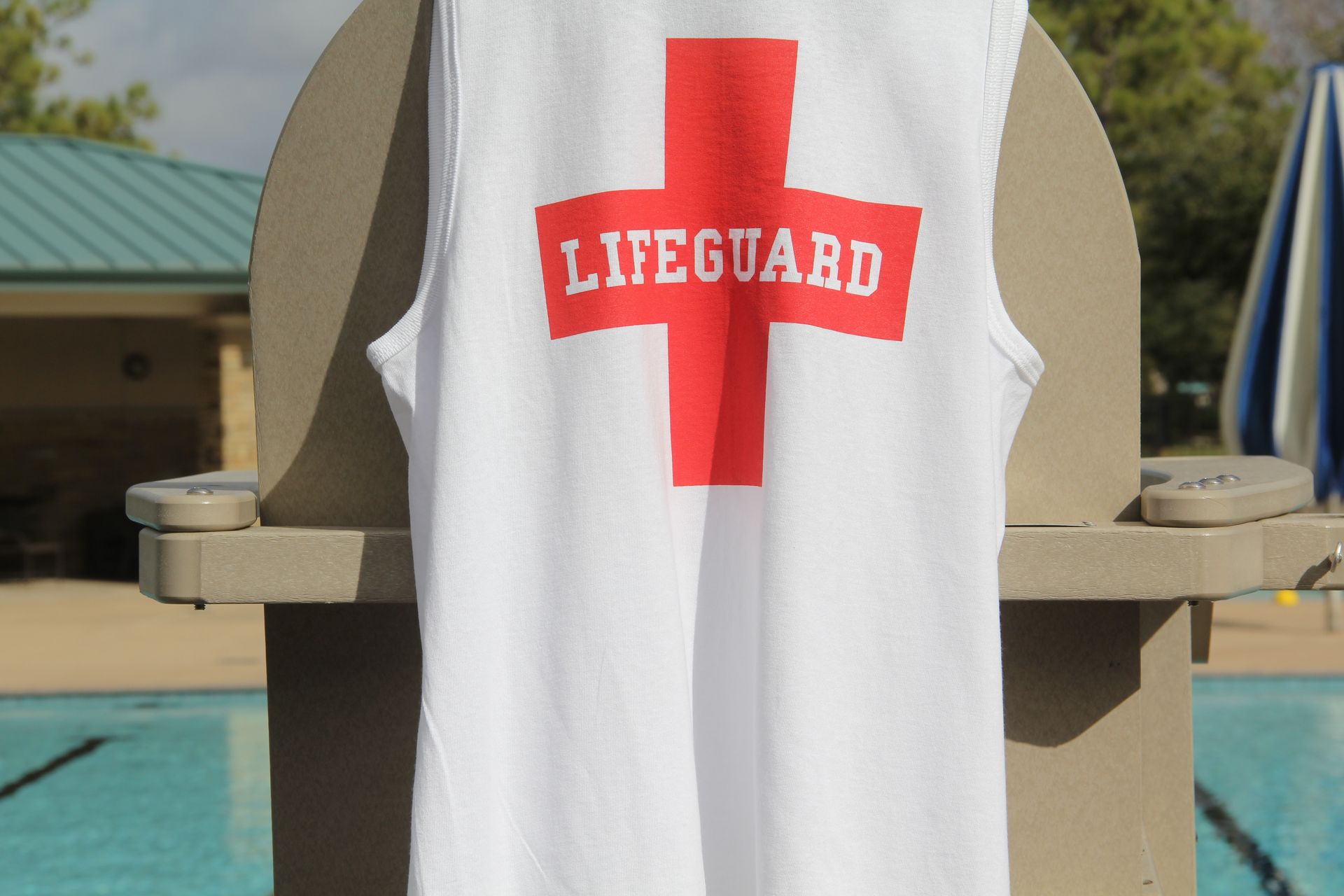 A man wearing a hat and a blue shirt is standing with his arms crossed and smiling.