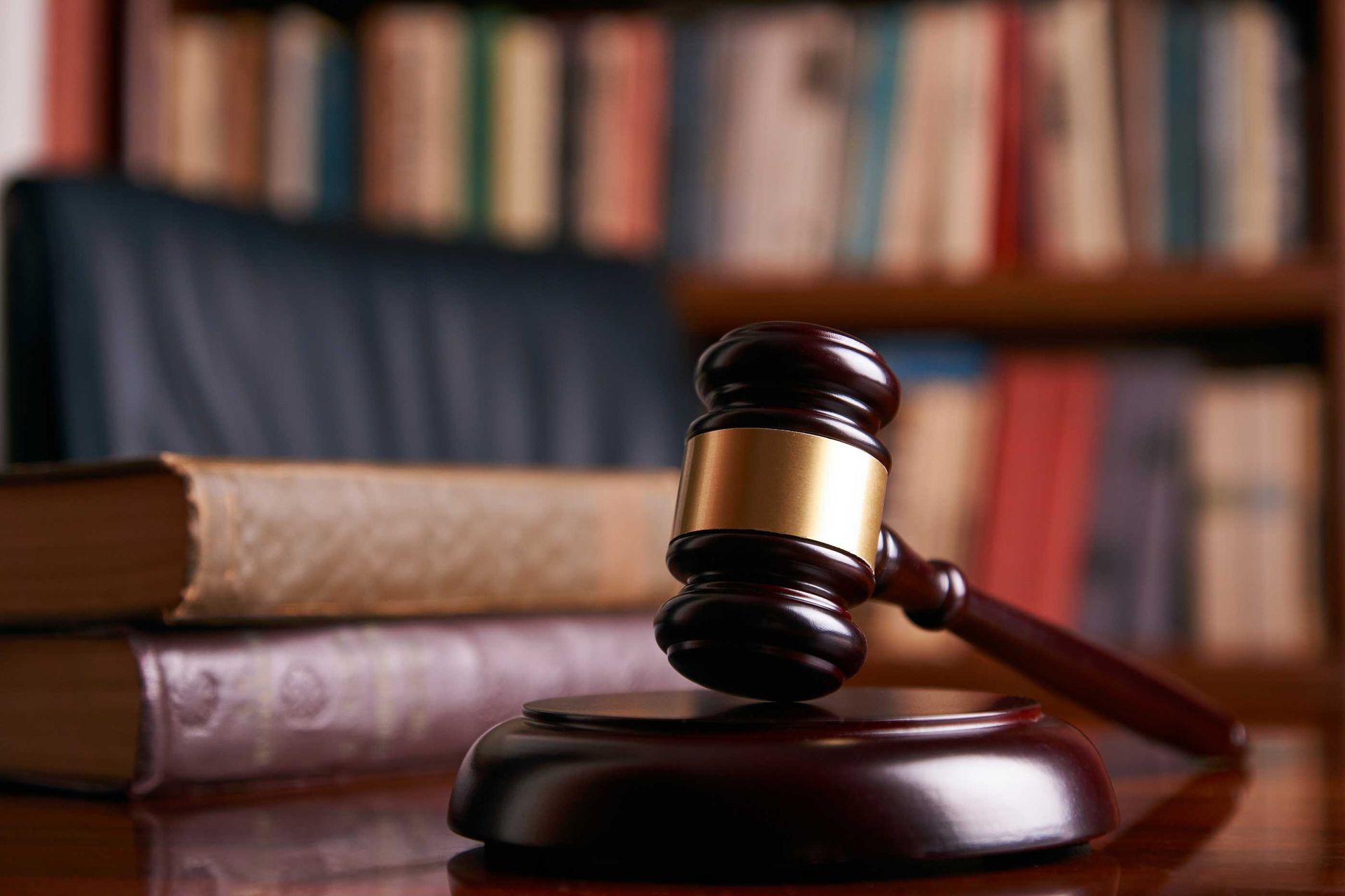 A judge 's gavel is sitting on a wooden table next to a stack of books.