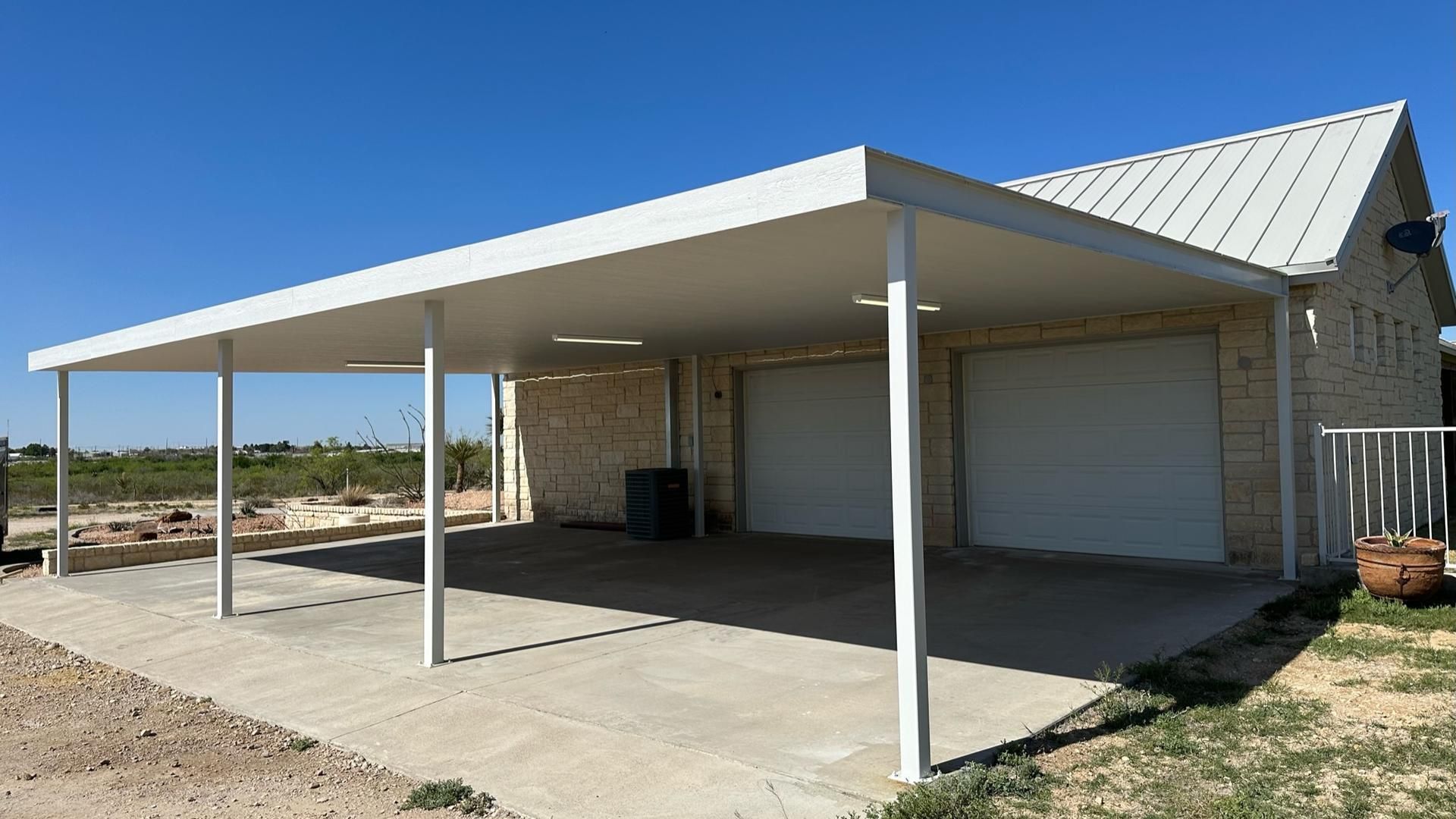 White carport covering a concrete driveway in front of a two-car garage with a light-colored brick exterior