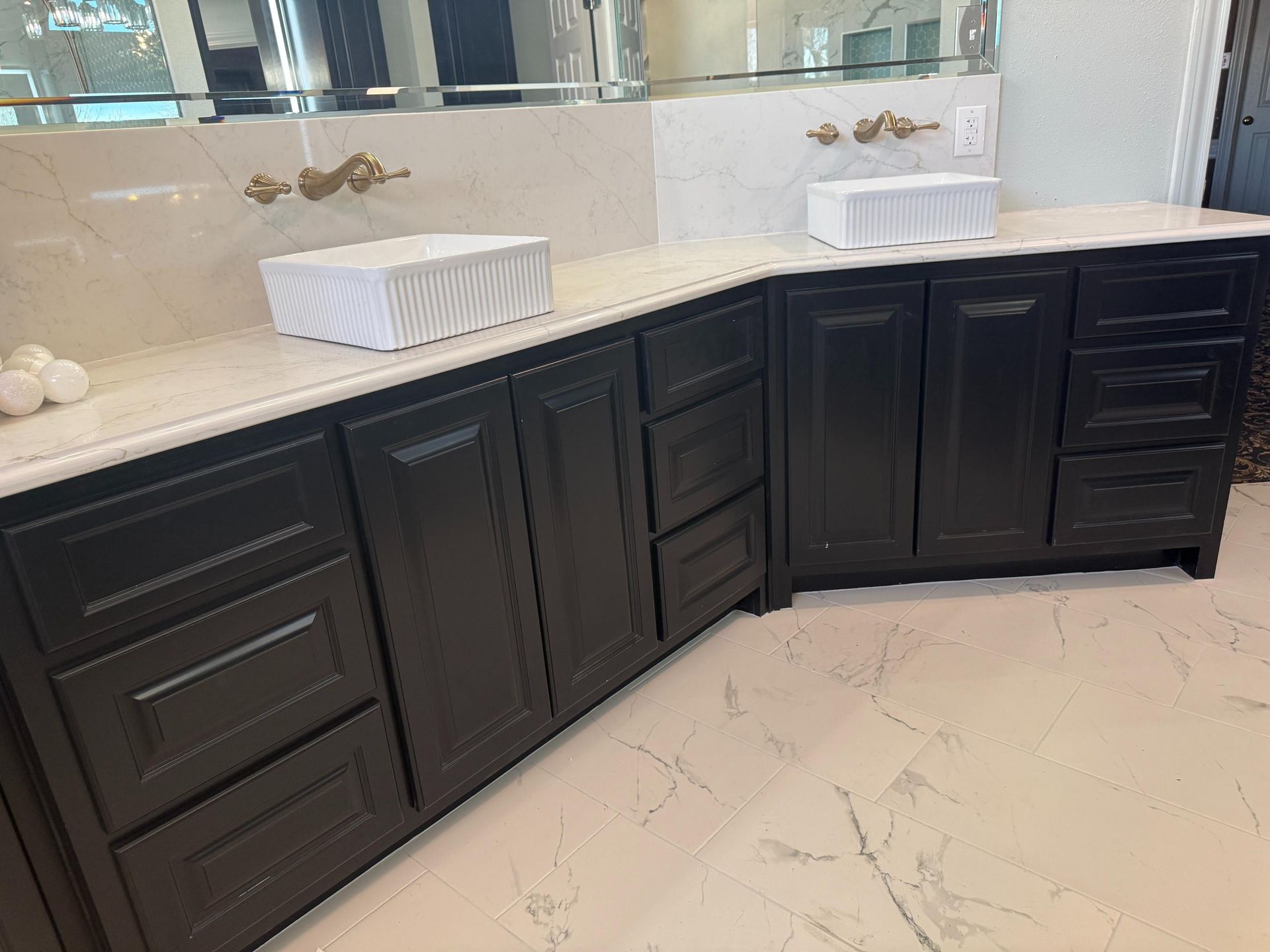 Dark wood bathroom vanity with two white sinks on a light-colored countertop. Marble floor.