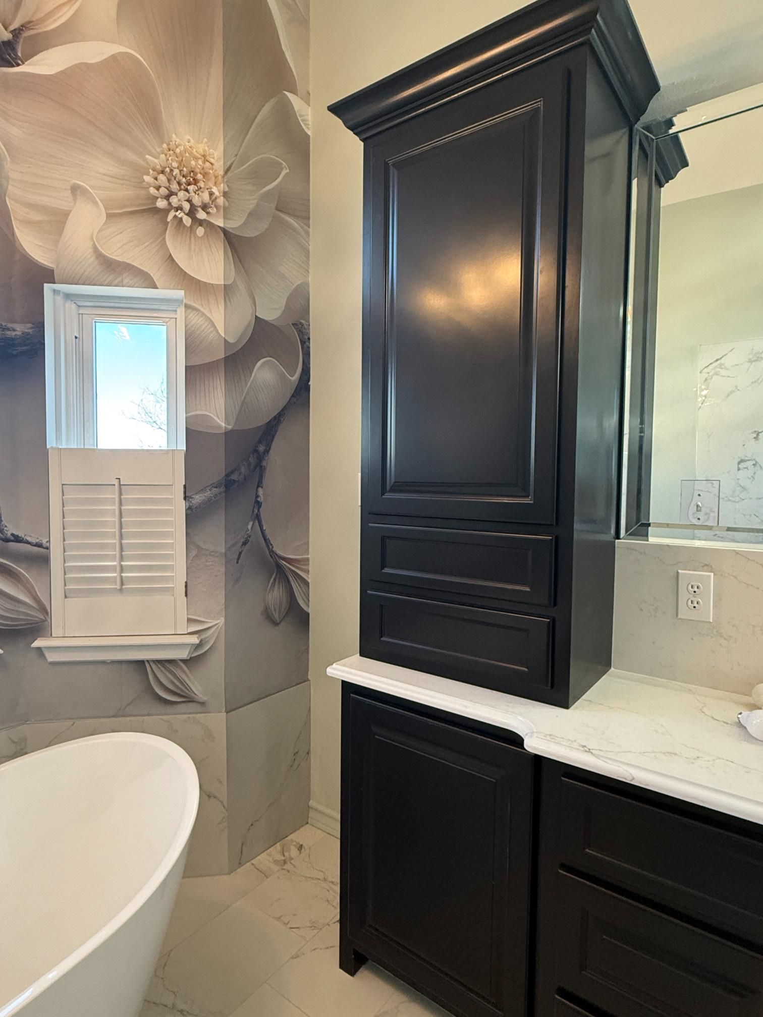 Bathroom with floral wallpaper, black storage cabinet, white countertop, and a soaking tub.