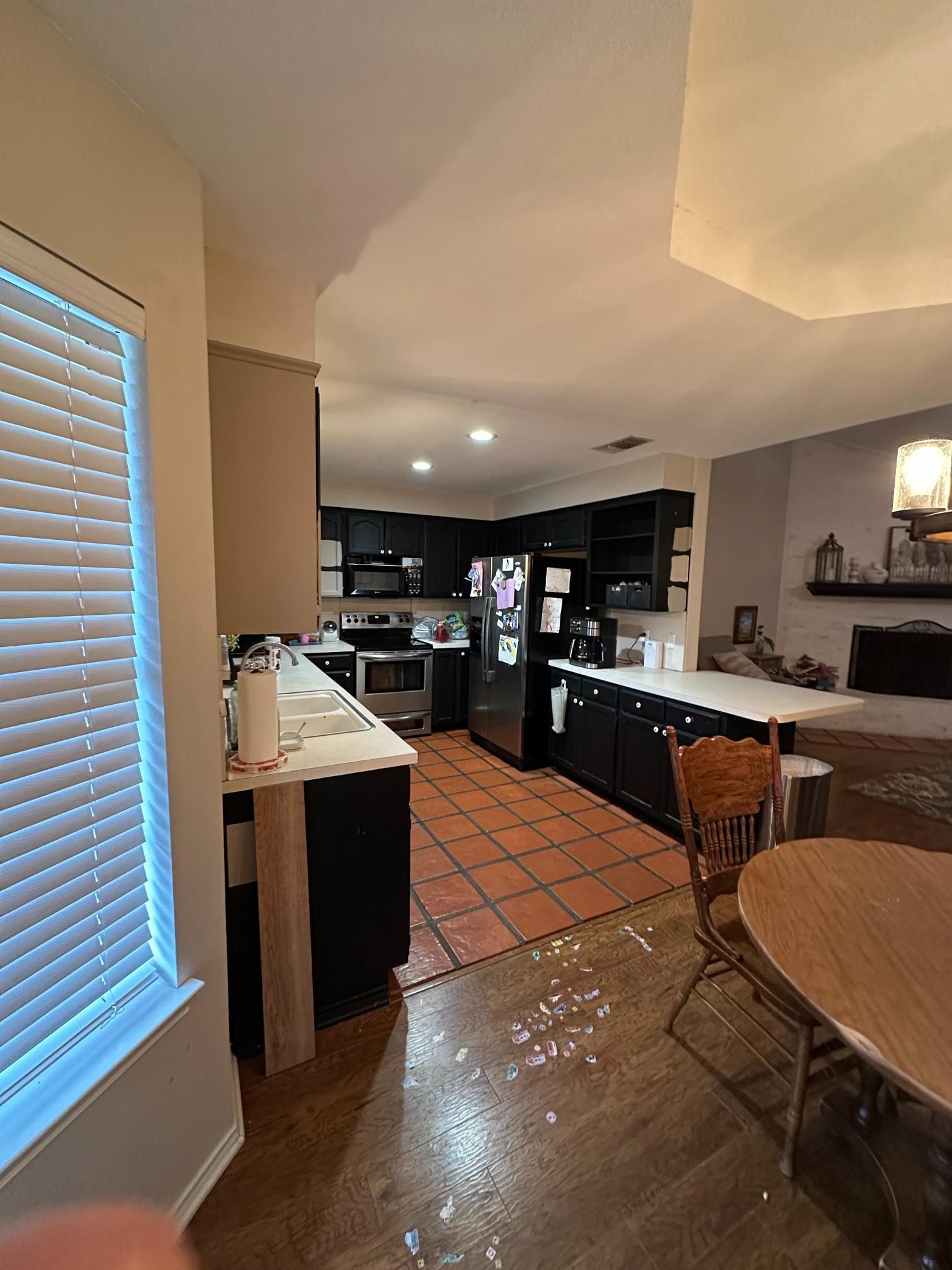 Kitchen with black cabinets, white countertops, tile and wood floors, and a dining table.
