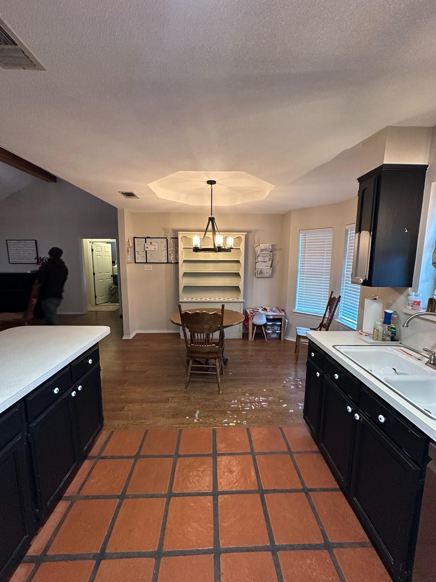 Kitchen with dark cabinets, a tile floor, and a dining area with a wood table.