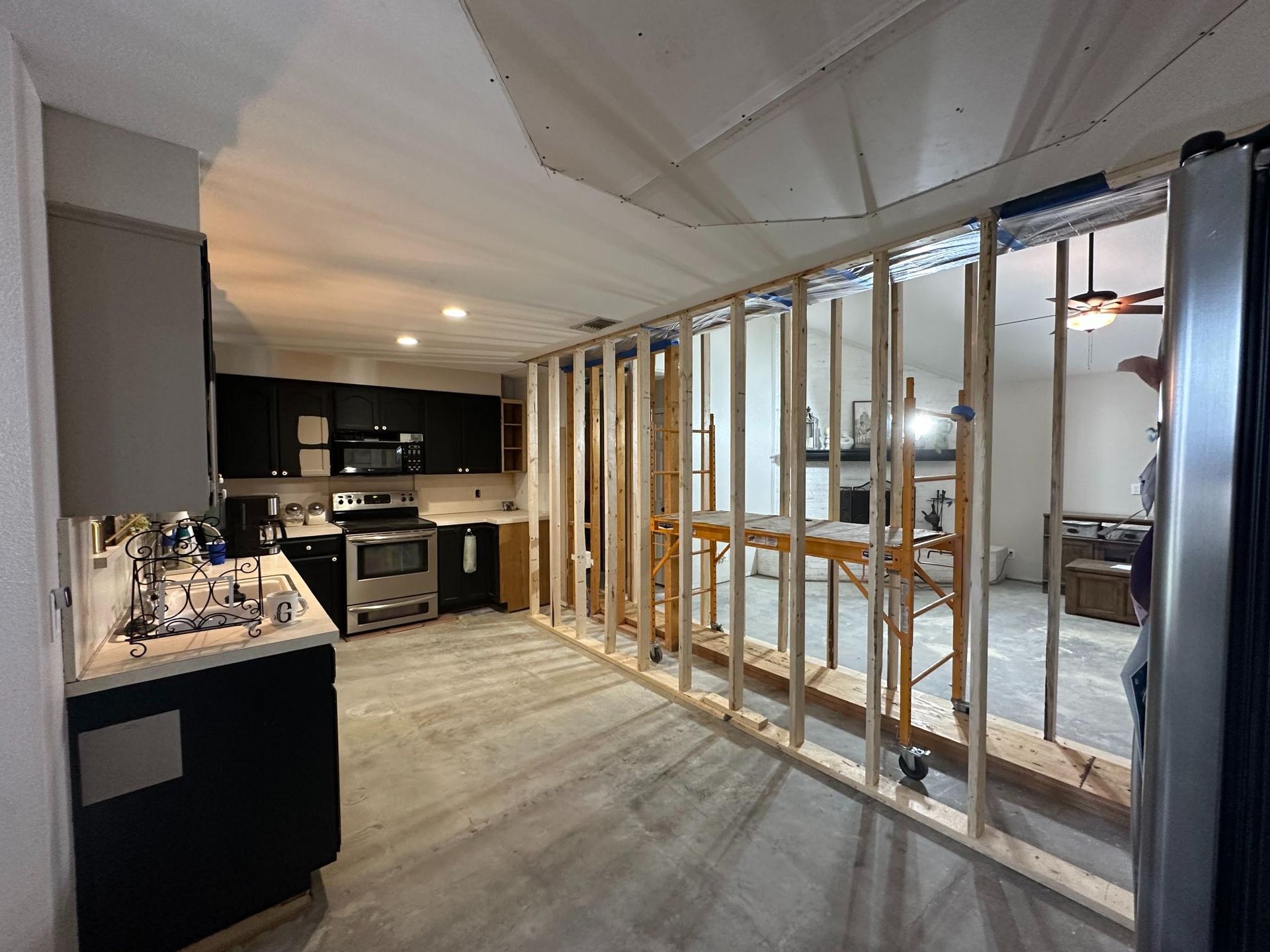 Kitchen under renovation. Framing erected between kitchen and living space, showing appliances and cabinetry.
