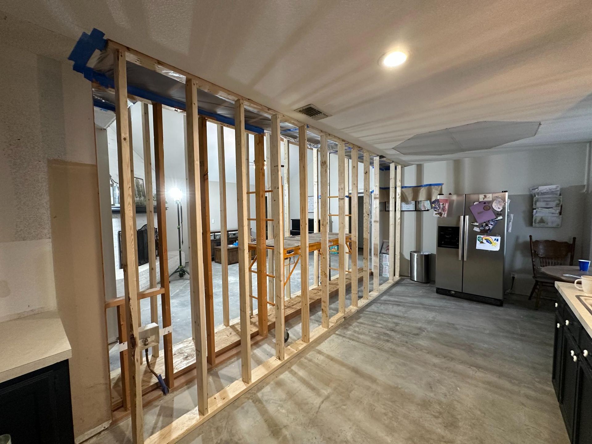 Interior view: wooden frame of a new wall being built in a kitchen, next to a refrigerator.