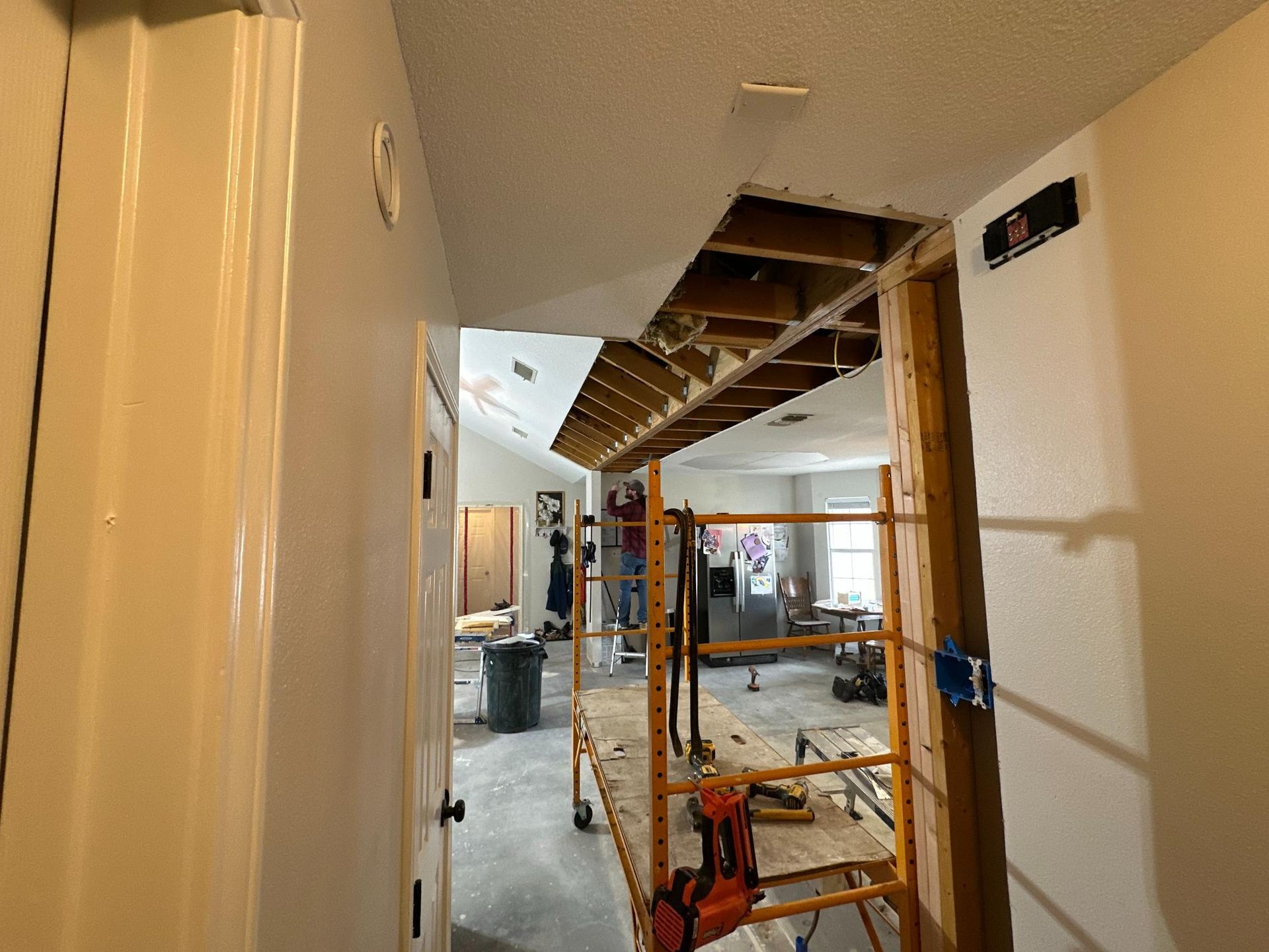Hallway under construction: ceiling open, scaffolding, workers in background.