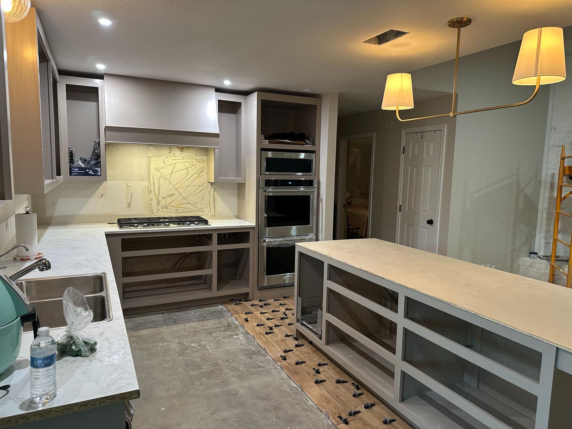 Kitchen renovation in progress: cabinets, island, appliances, and countertops visible.
