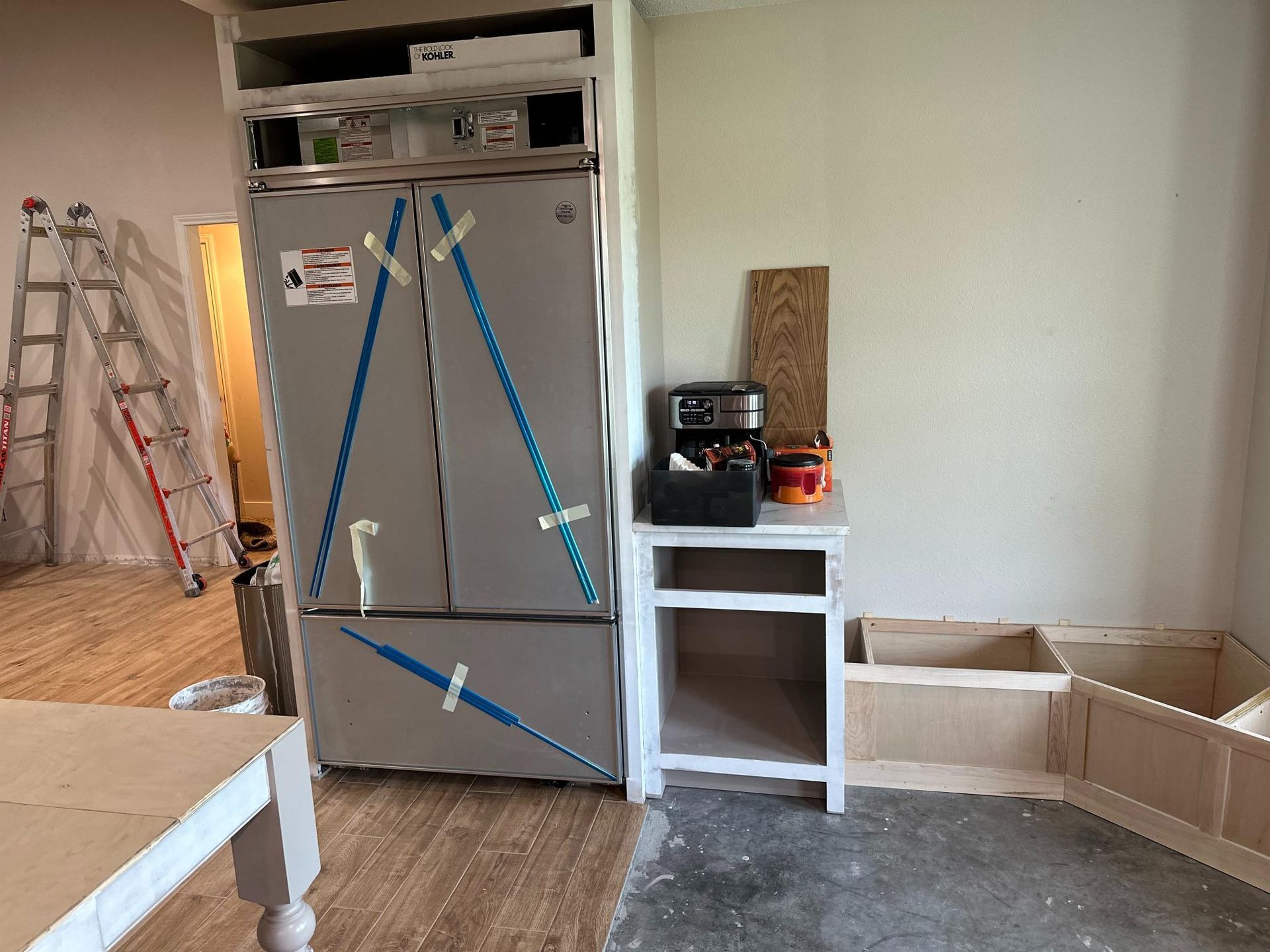 Kitchen under renovation with refrigerator, cabinet, and unfinished built-in.
