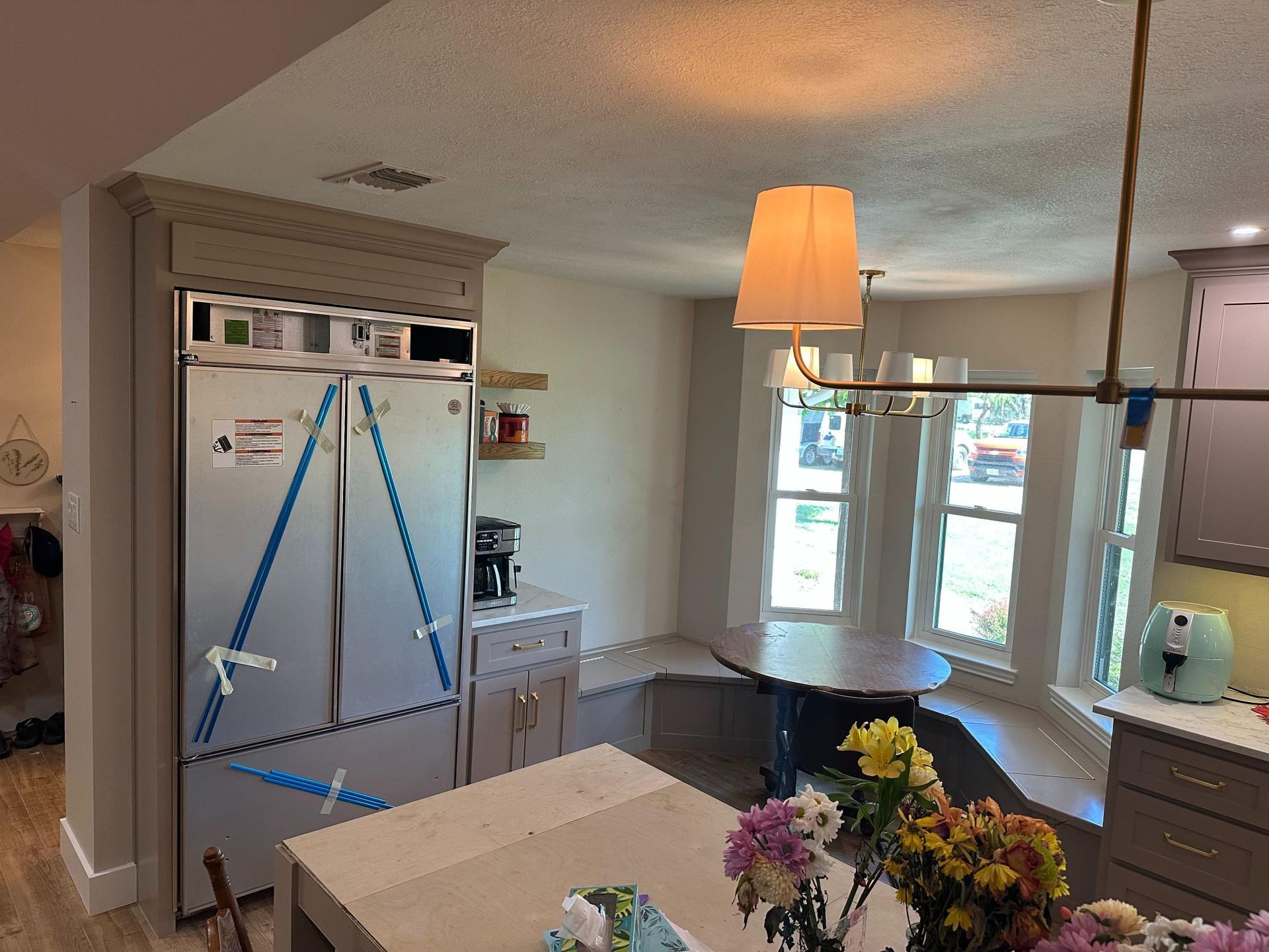 Kitchen with stainless steel refrigerator, round table by a window, and overhead light.