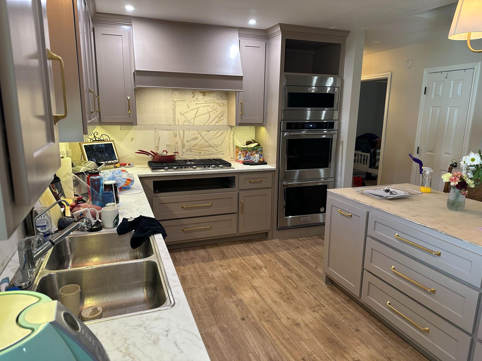 A modern kitchen with grey cabinets, stainless steel appliances, and a central island.