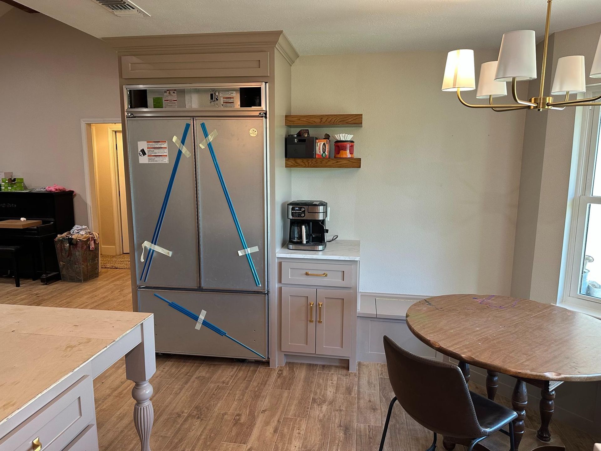 Kitchen with refrigerator, cabinets, coffee maker, round table, and a chandelier.