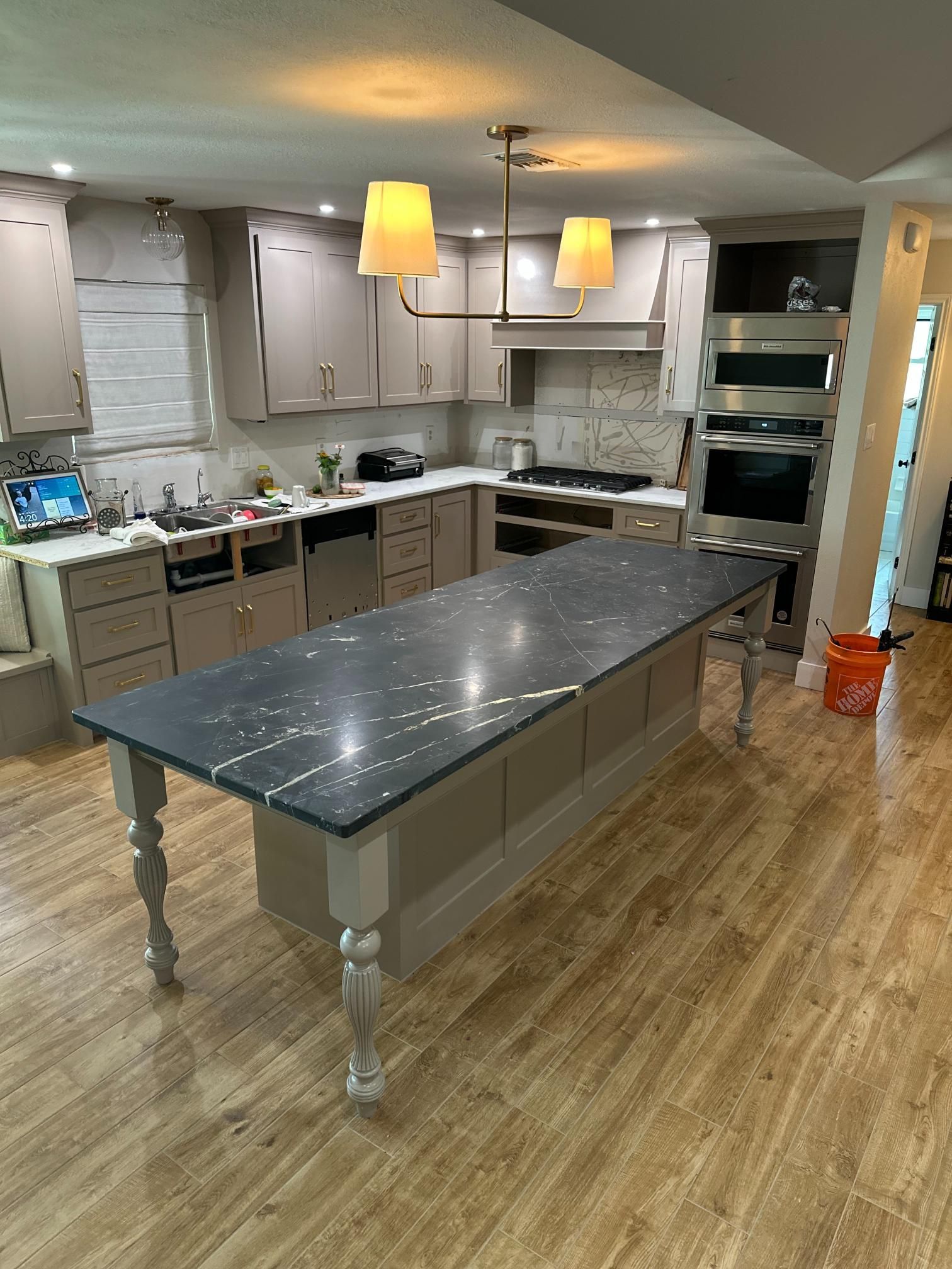 Kitchen with light gray cabinets, a dark countertop island, and light wood flooring.