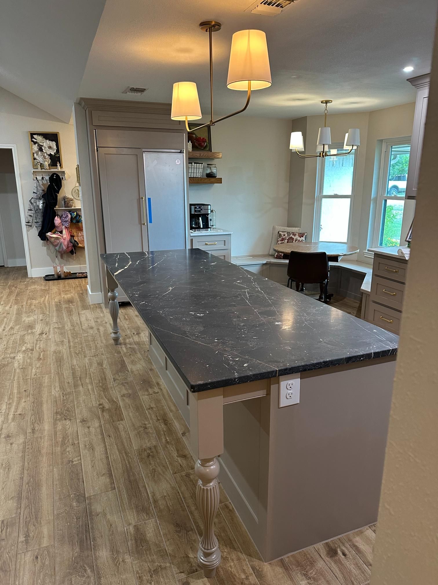 Kitchen island with gray countertop, taupe cabinets, and two pendant lights above.