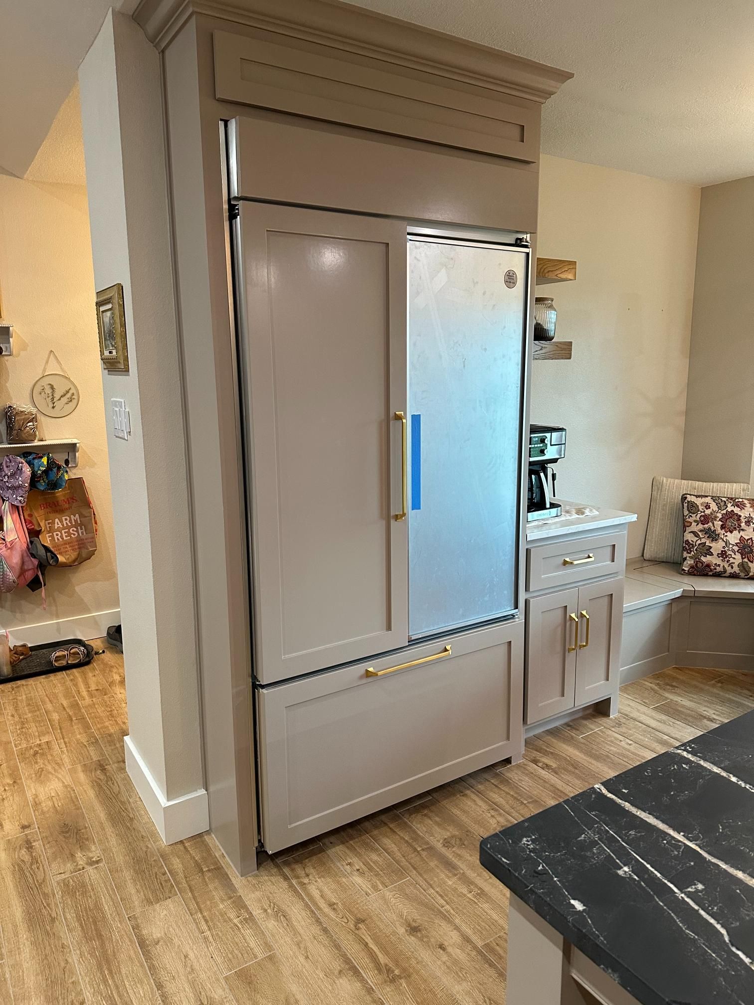 Beige-toned refrigerator built into a kitchen cabinet, with a small cabinet beside it.