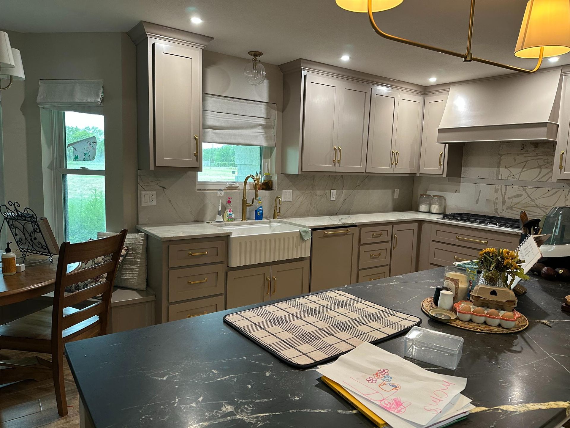Kitchen with light gray cabinets, white countertops, black island, and window.