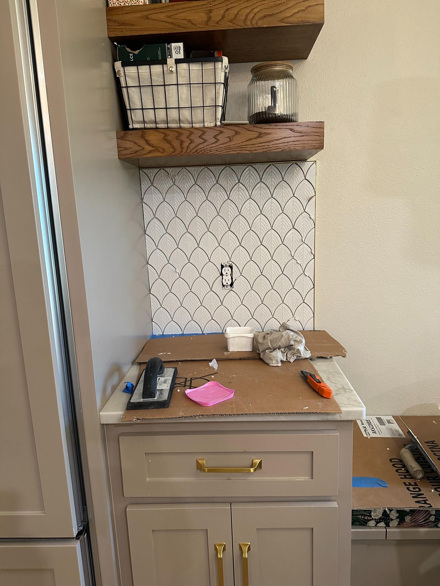 Kitchen renovation with installed tile backsplash, cabinets, and shelving.
