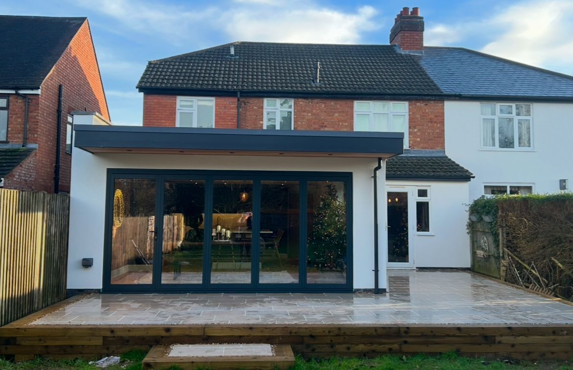 A brick house with a slate roof and a blue door is being built.