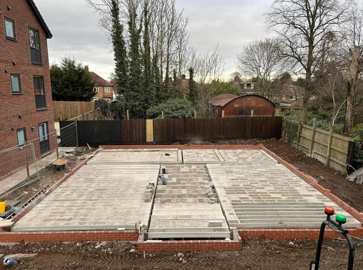A concrete base for a house is being built in a backyard.