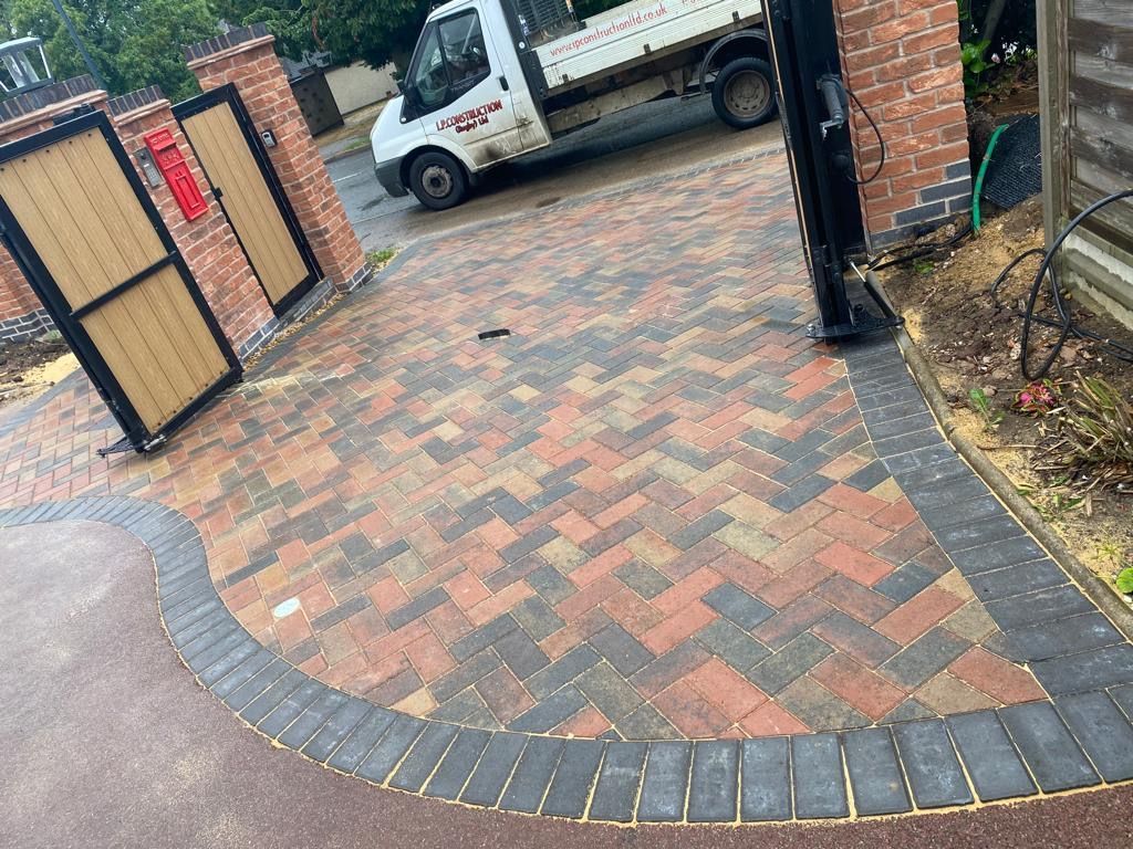 A white truck is parked in a driveway next to a brick wall.