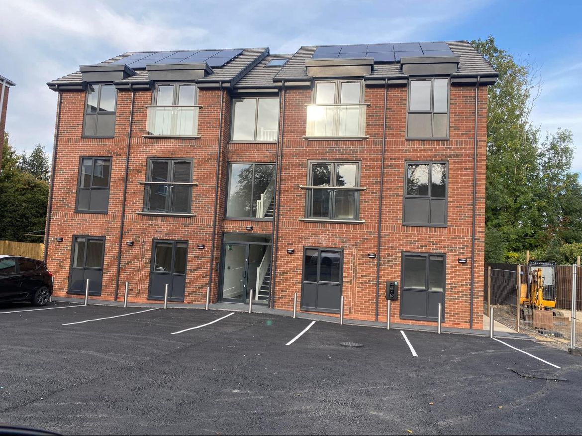 A large brick building with a lot of windows and a parking lot in front of it.