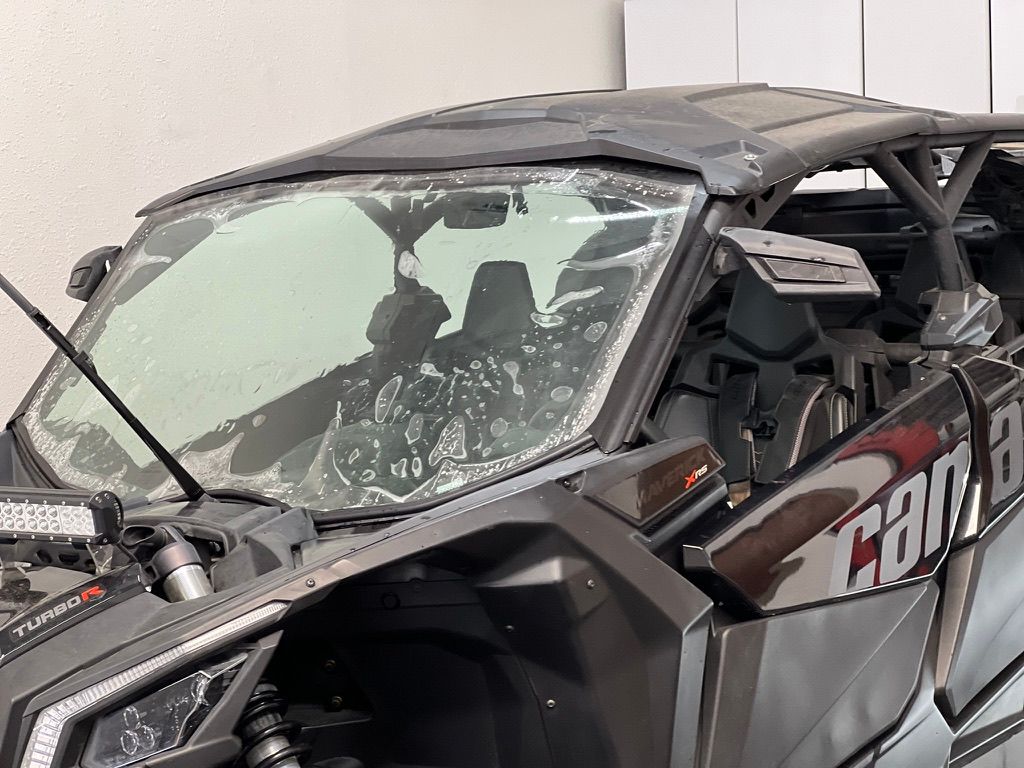 A silver sports car with a black top is parked in a garage