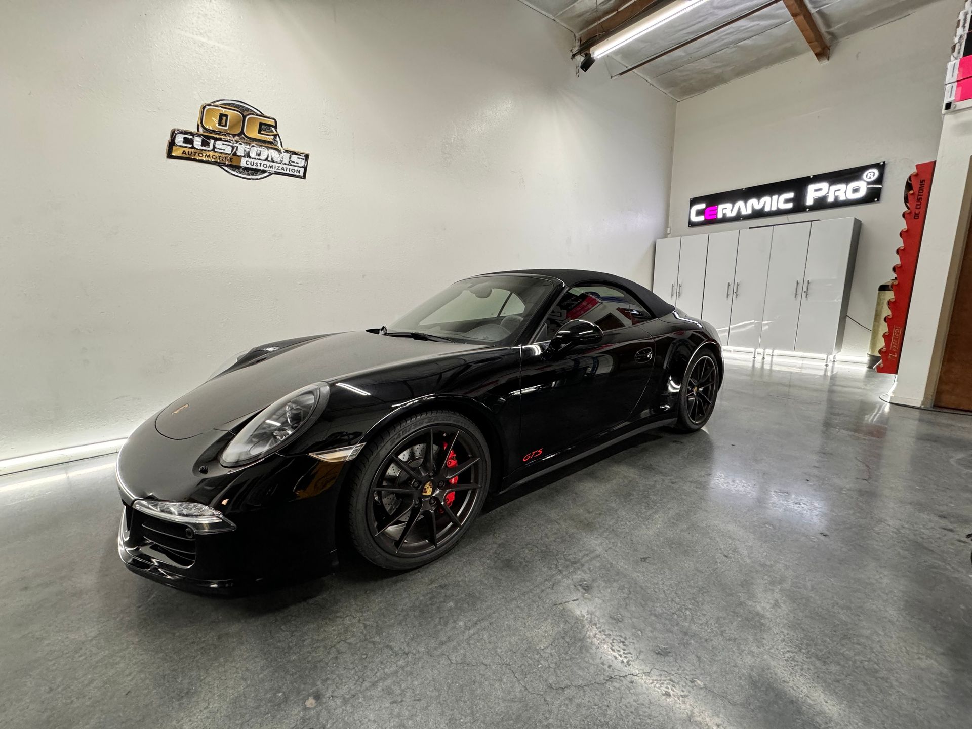 A black porsche 911 carrera is parked in a garage.