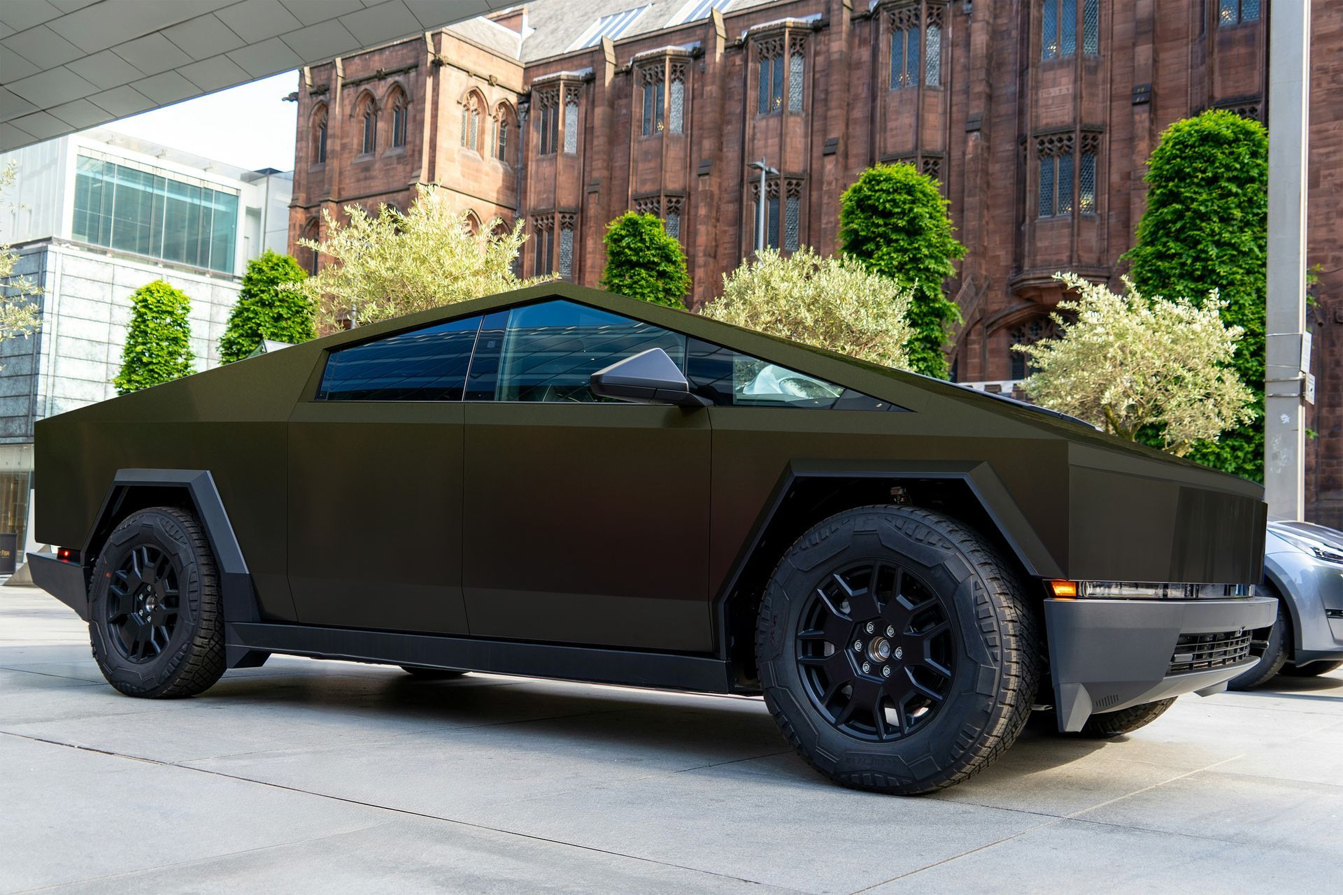 A black car is parked in front of a brick building.