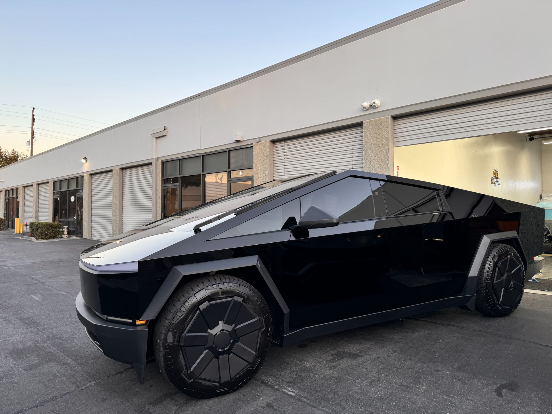 A black tesla cybertruck is parked in front of a building.