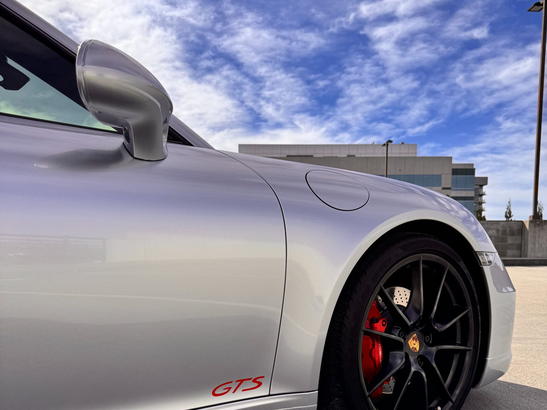 A silver porsche 911 gts is parked on the side of the road.