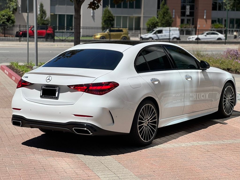 A white mercedes benz c class is parked on the side of the road.