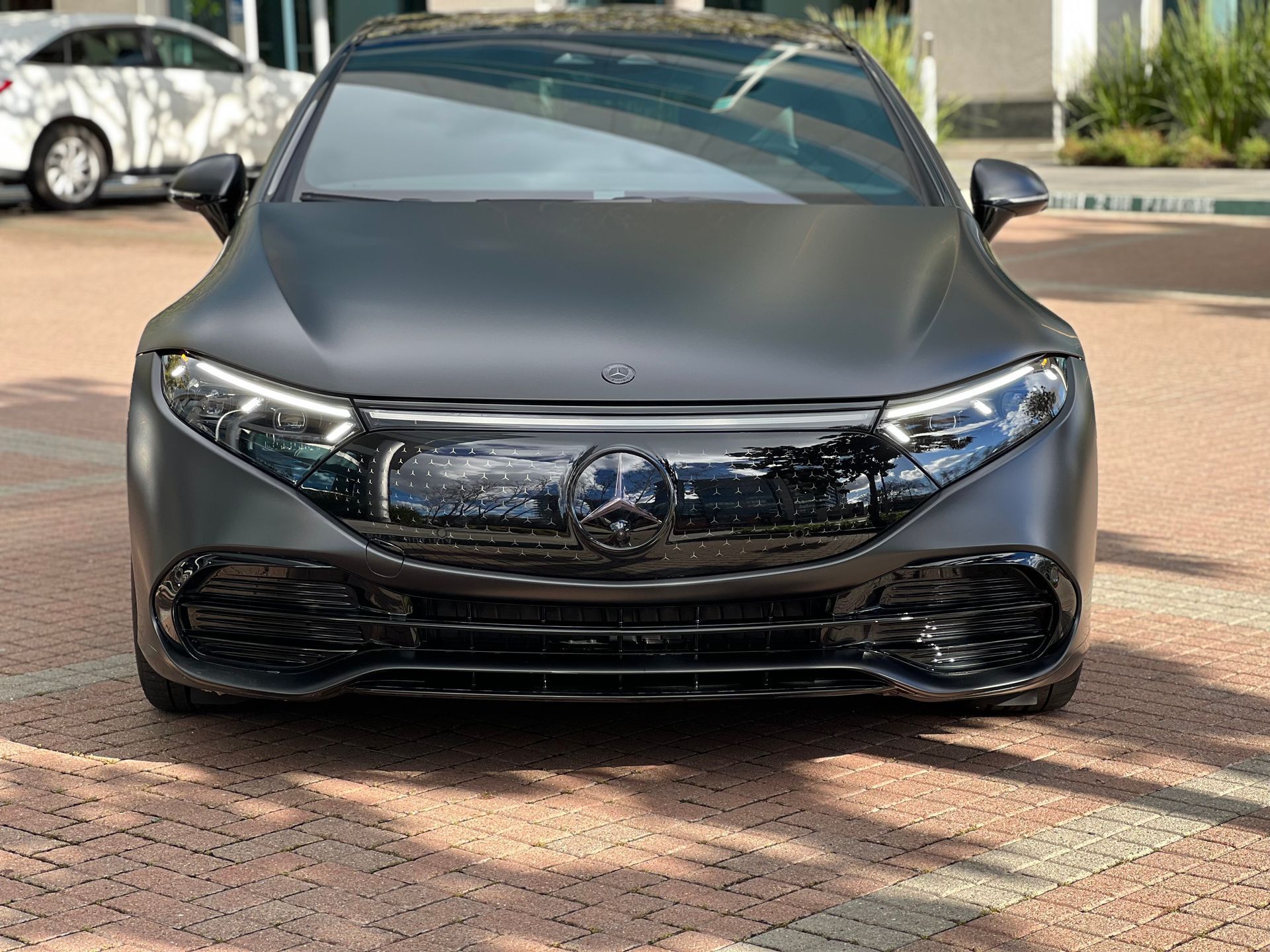 A black mercedes benz eqs is parked on a brick driveway.