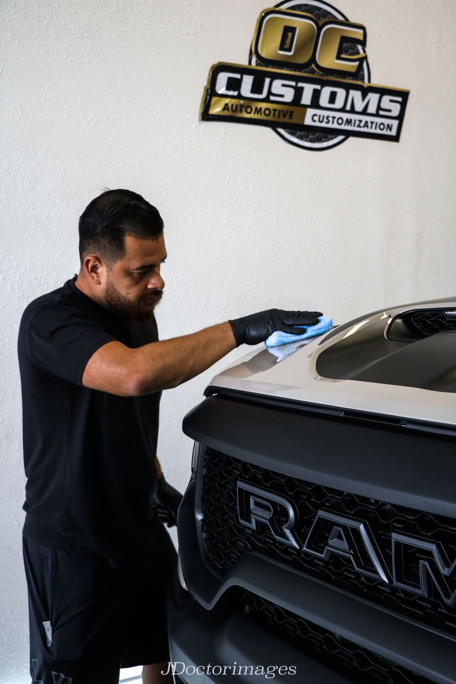 A man is cleaning the hood of a ram truck.