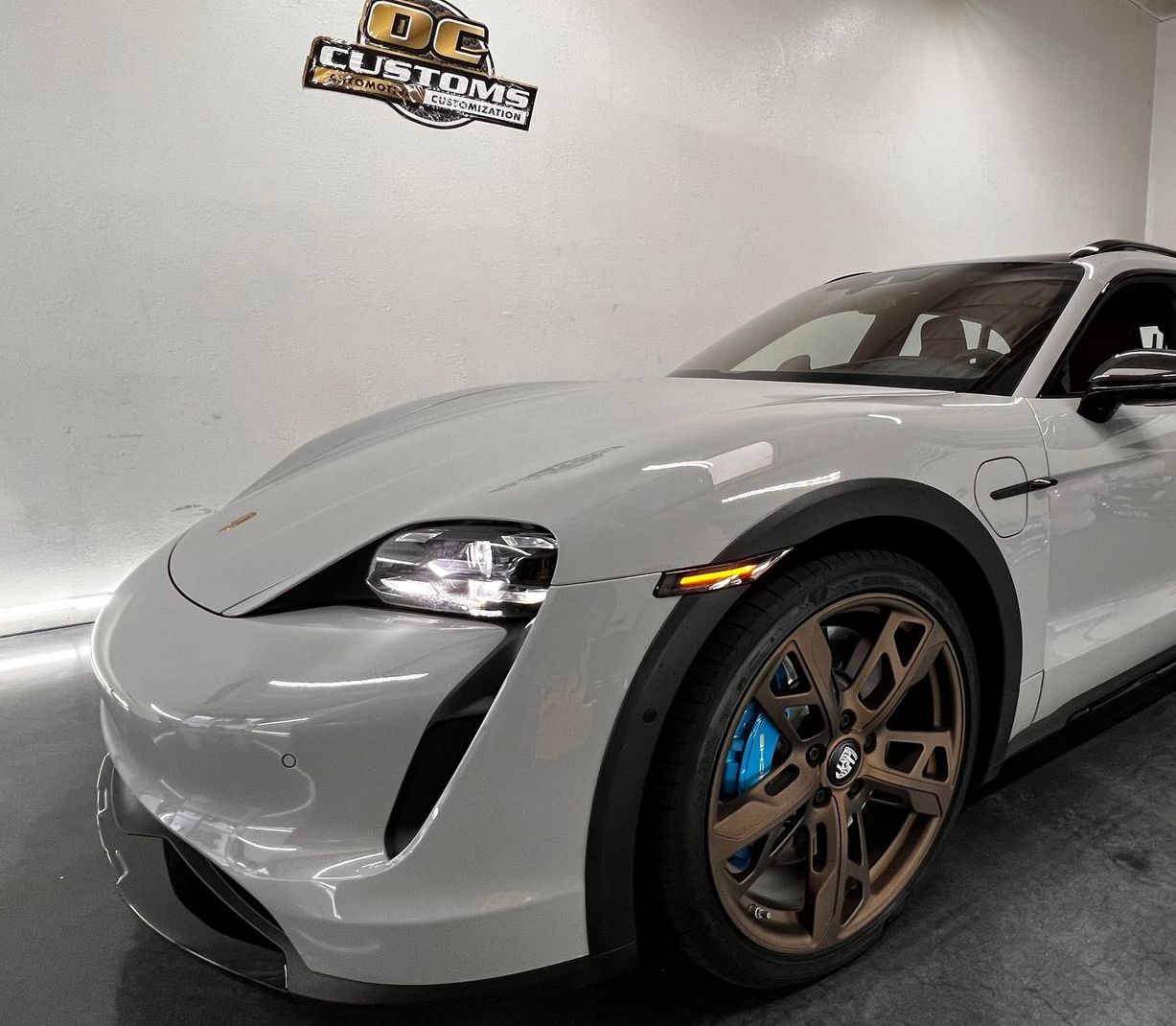 A black gmc truck is sitting in a garage with its headlights covered in plastic.