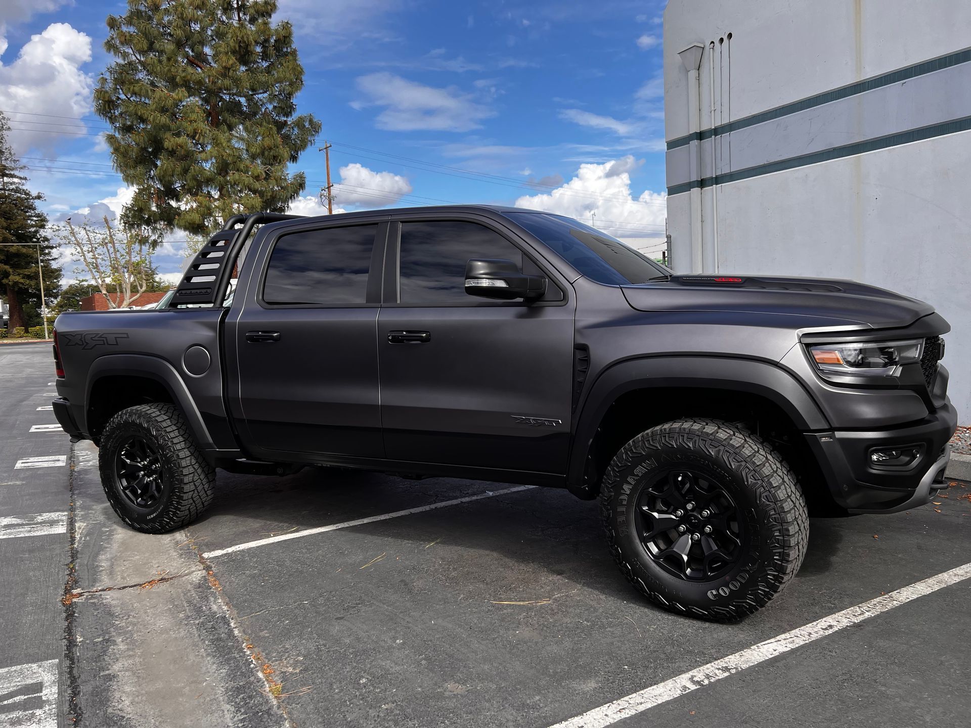 A black truck is parked in a parking lot in front of a building.