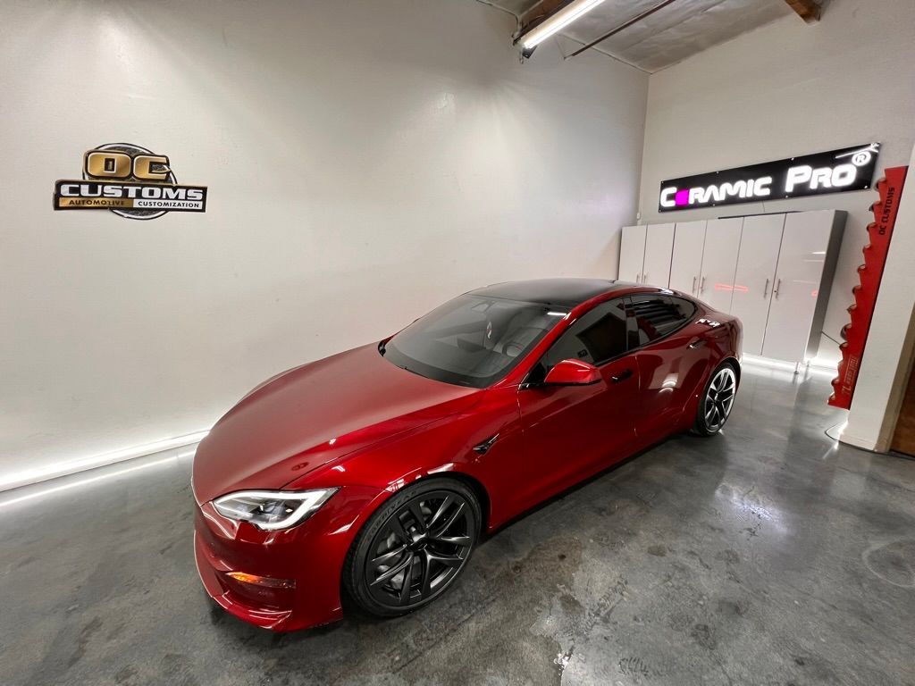 A red tesla model s is parked in a garage.