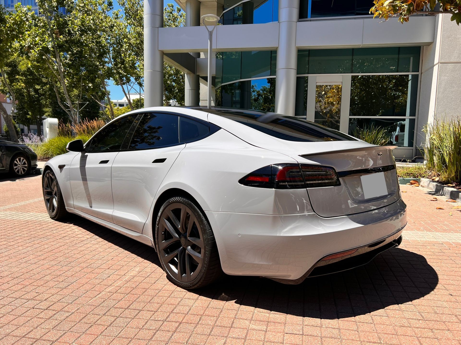 A white tesla model s is parked in front of a building.