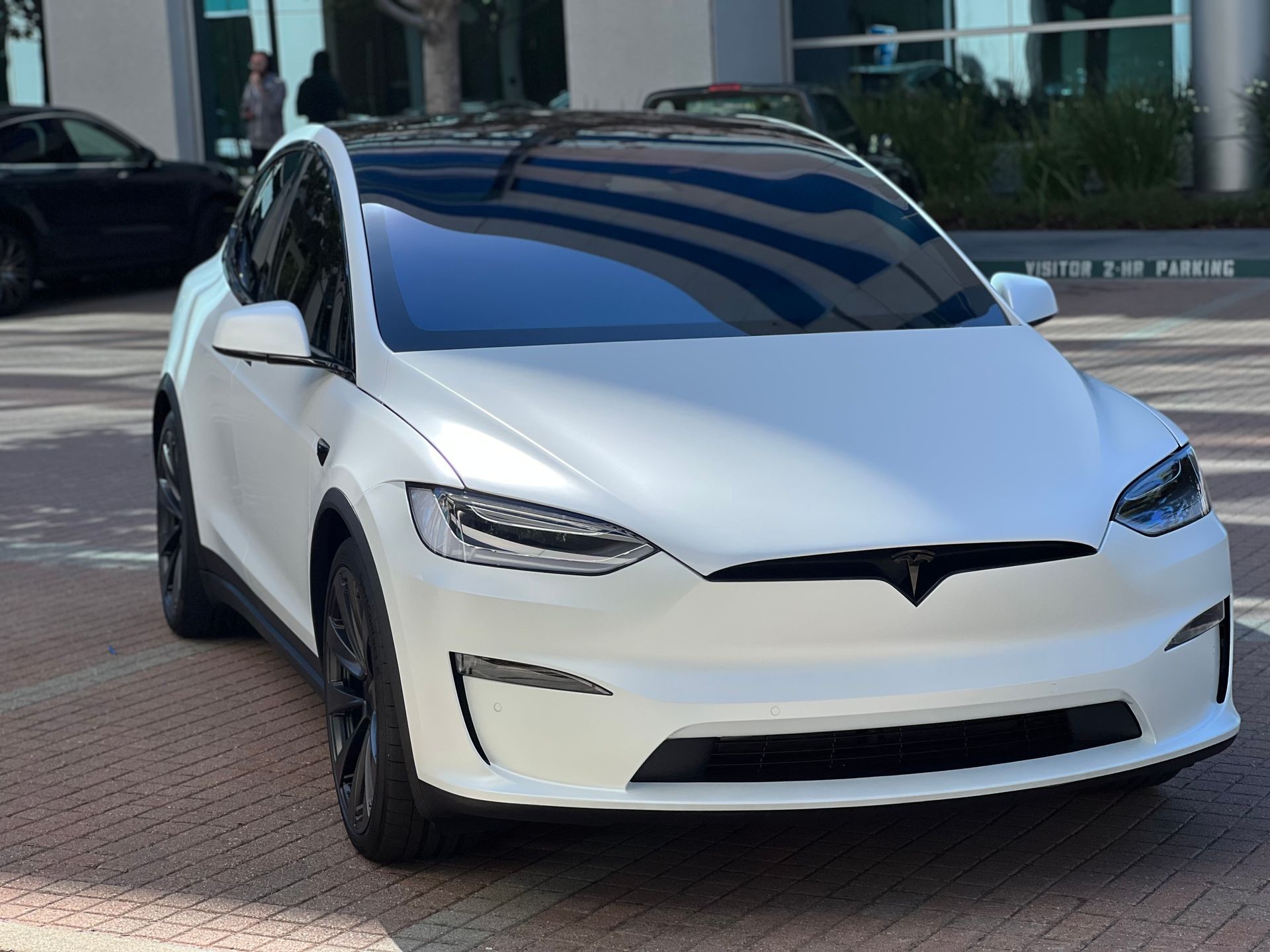 A white tesla model x is parked in a parking lot