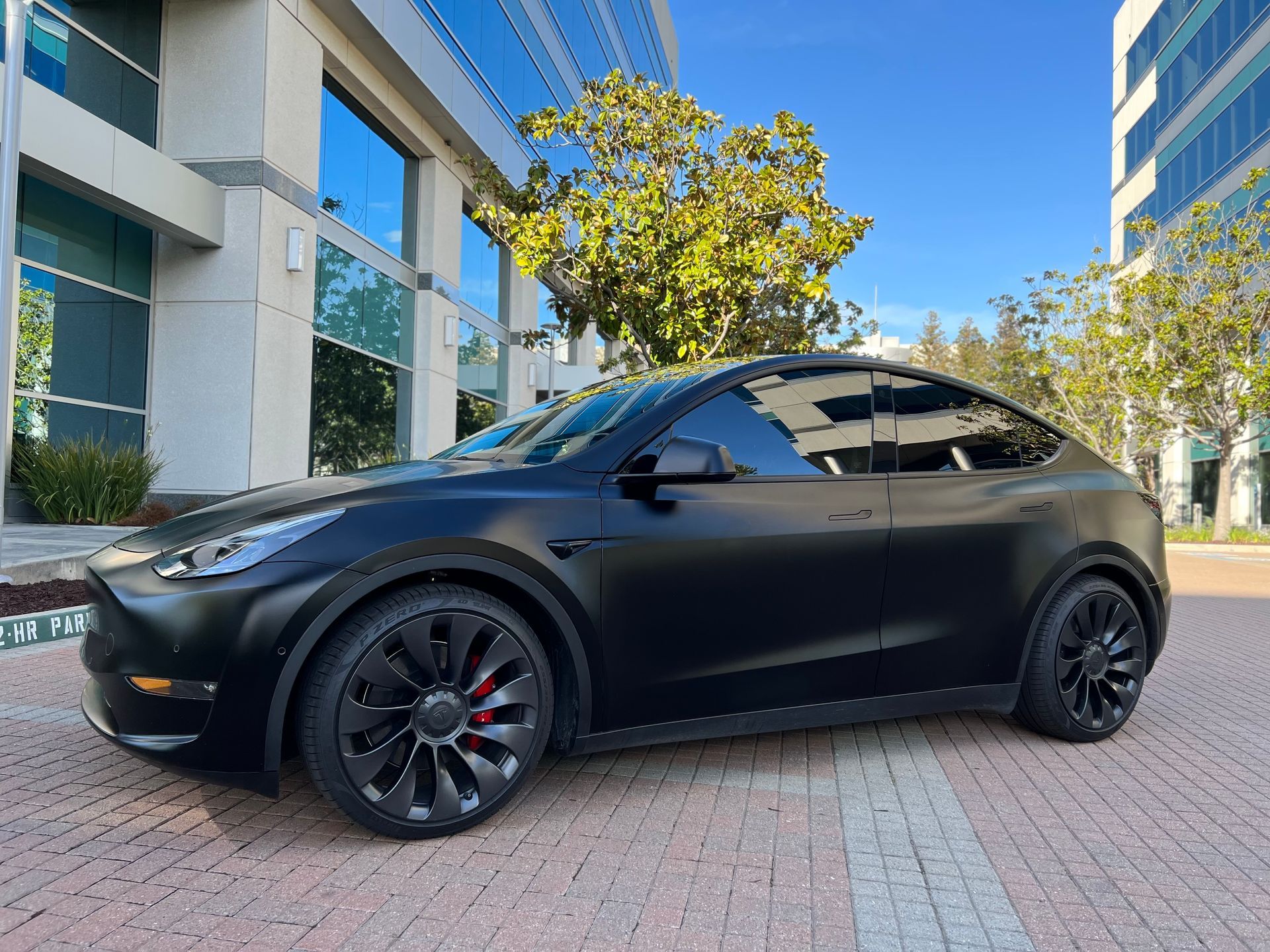 A black tesla model y is parked in front of a building.