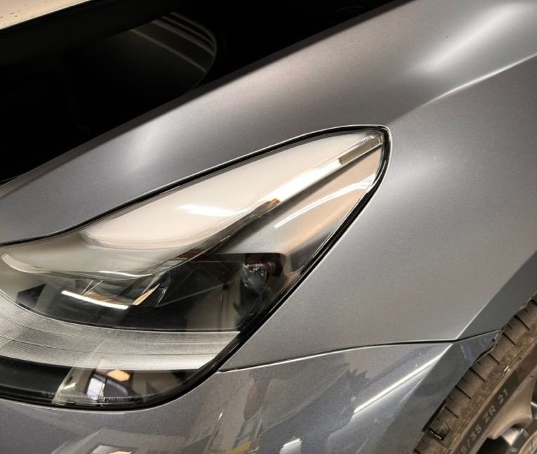 A close up of the headlight of a silver car