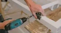 Albañil manipulando las visagras de una ventana que está a punto de colocar en la casa de un cliente en Castellón