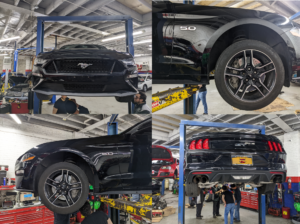 A black mustang is on a lift in a garage