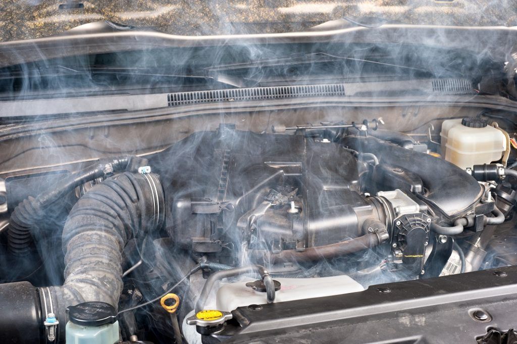 Smoke is coming out of the engine of a car.