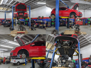 A red car is sitting on a lift in a garage.