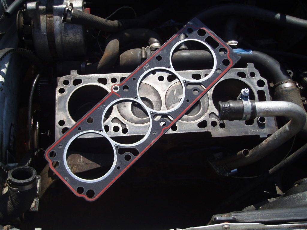 A cylinder head gasket is sitting on top of a car engine
