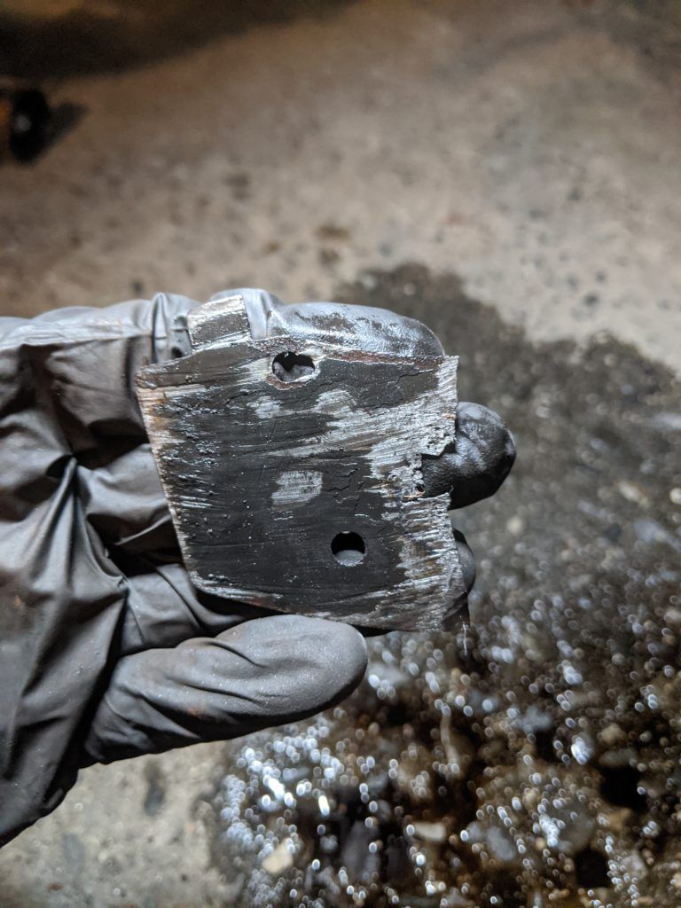 A person wearing black gloves is holding a piece of metal in their hand.