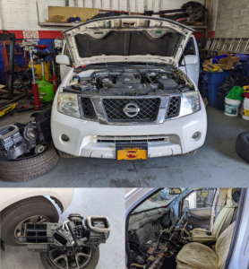 A white nissan truck with the hood open in a garage